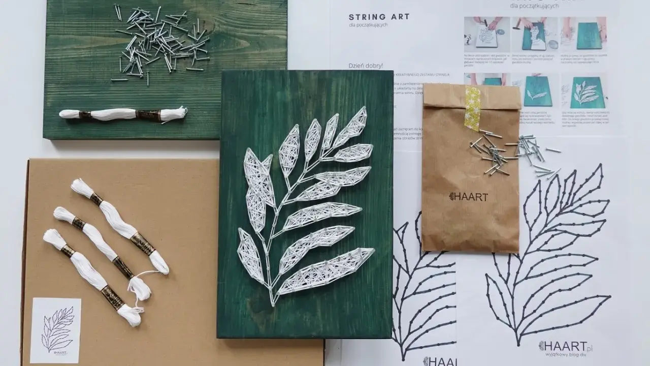Zestaw do tworzenia obrazów string art z motywem liścia. W pudełku deska, gwoździe, biała nić i instrukcja.